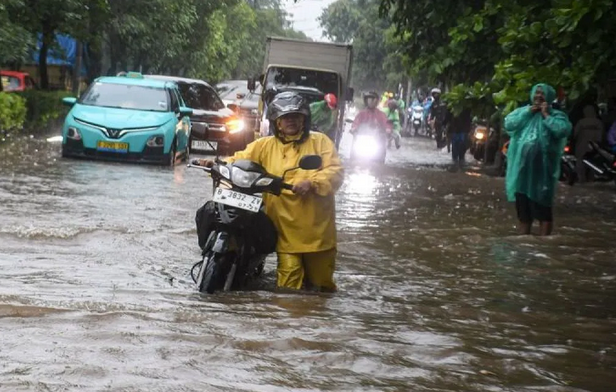 Warga mendorong sepeda motor melintasi genangan banjir di Sunter, Jakarta Utara, Januari 2026